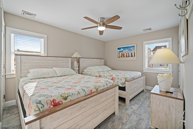 bedroom featuring multiple windows, hardwood / wood-style floors, and ceiling fan