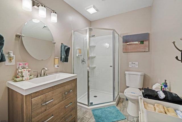 bathroom with vanity, hardwood / wood-style flooring, a shower with door, and toilet