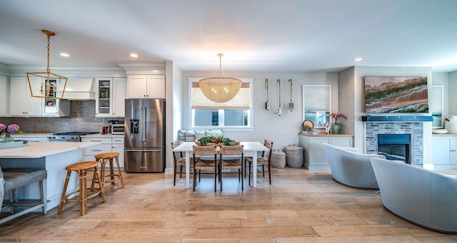 kitchen with appliances with stainless steel finishes, pendant lighting, white cabinets, decorative backsplash, and custom range hood