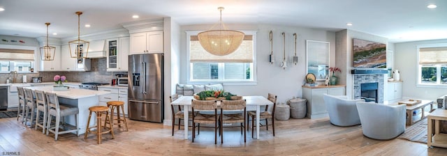 kitchen with tasteful backsplash, decorative light fixtures, a center island, light hardwood / wood-style flooring, and stainless steel appliances