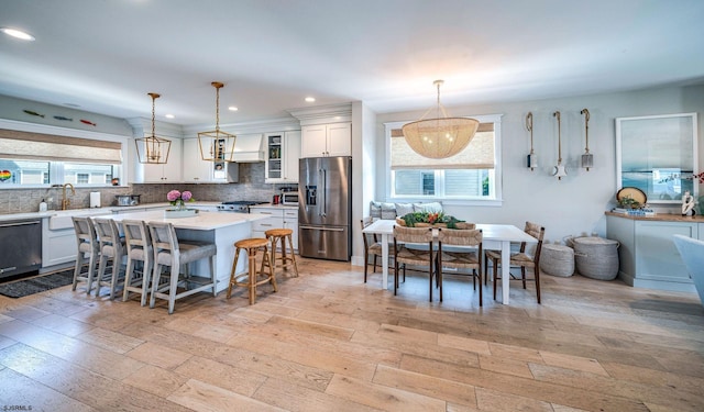 kitchen with white cabinetry, tasteful backsplash, appliances with stainless steel finishes, a kitchen island, and pendant lighting