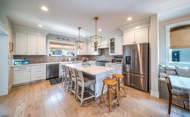 kitchen with high end appliances, white cabinetry, pendant lighting, and a kitchen island