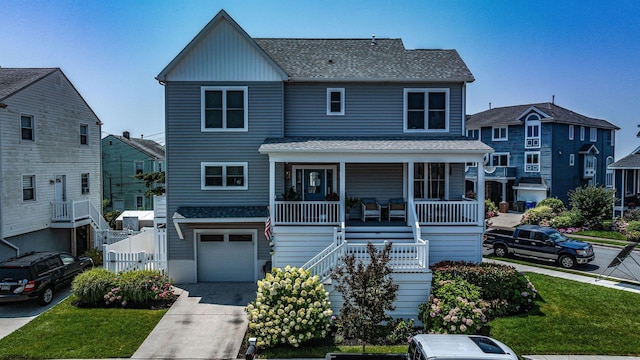 view of front of house with a garage, a front yard, and a porch