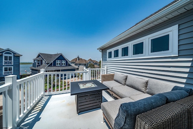 view of patio with a water view and an outdoor living space with a fire pit