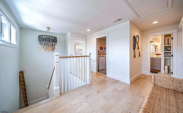 corridor with washer / dryer and light hardwood / wood-style flooring