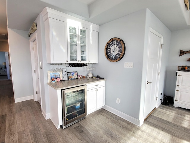 bar featuring wine cooler, visible vents, baseboards, light wood-type flooring, and a bar