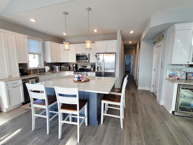 kitchen with stainless steel appliances, backsplash, white cabinetry, a sink, and beverage cooler