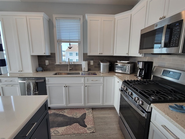 kitchen featuring a toaster, white cabinetry, stainless steel appliances, and a sink