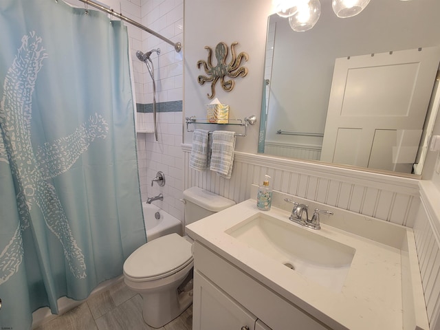 full bathroom featuring toilet, a wainscoted wall, shower / bath combo, and vanity