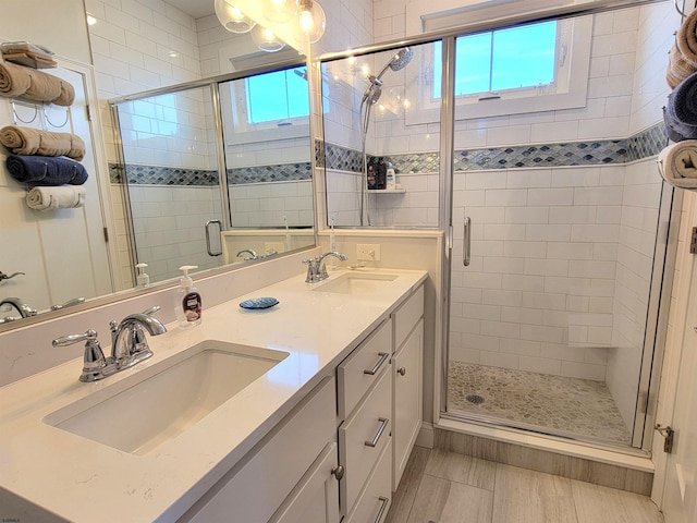 full bathroom featuring a stall shower, a sink, and double vanity