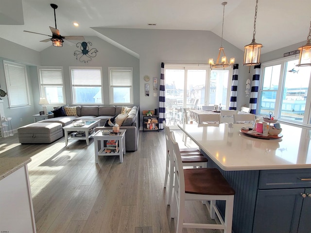 kitchen featuring a breakfast bar area, light wood-style flooring, open floor plan, light countertops, and vaulted ceiling