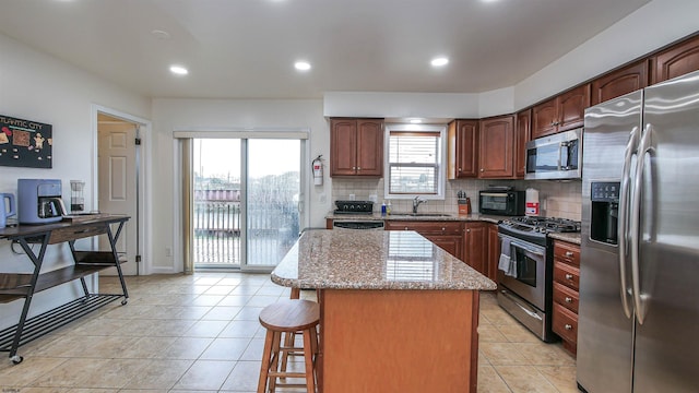 kitchen featuring stainless steel appliances, tasteful backsplash, a center island, and light tile patterned floors