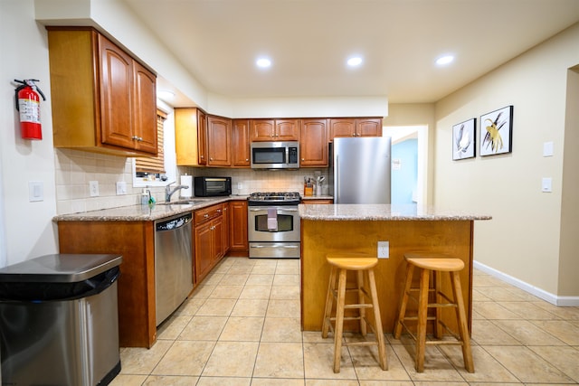 kitchen featuring light tile patterned flooring, appliances with stainless steel finishes, a kitchen island, and decorative backsplash