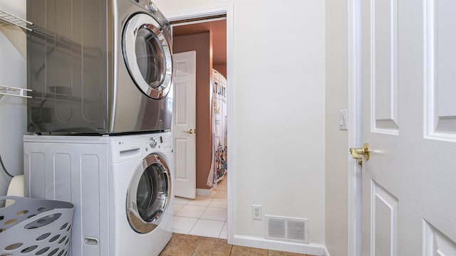 laundry area featuring stacked washer / drying machine and light tile patterned floors