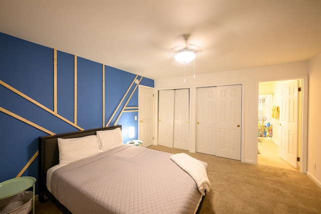 bedroom with multiple closets, ensuite bathroom, carpet flooring, and ceiling fan