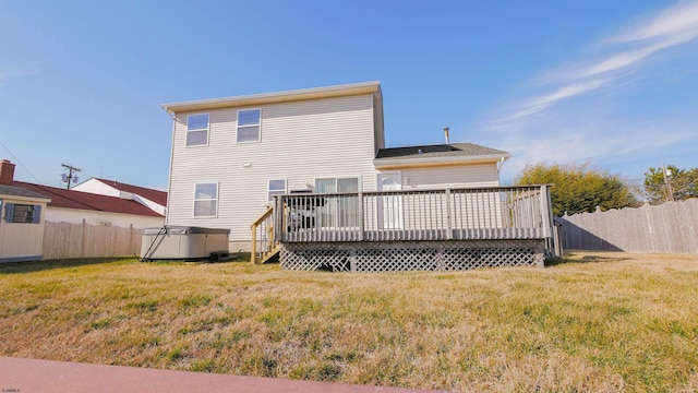 back of house featuring a yard, a hot tub, and a deck