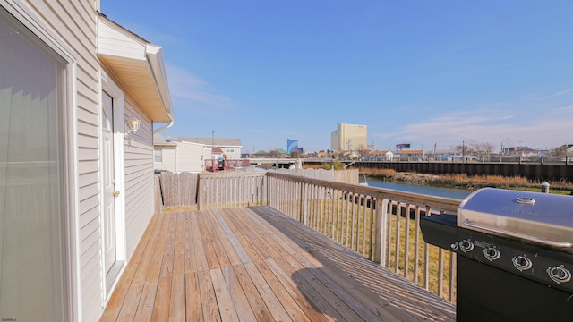 wooden deck with a water view and a grill