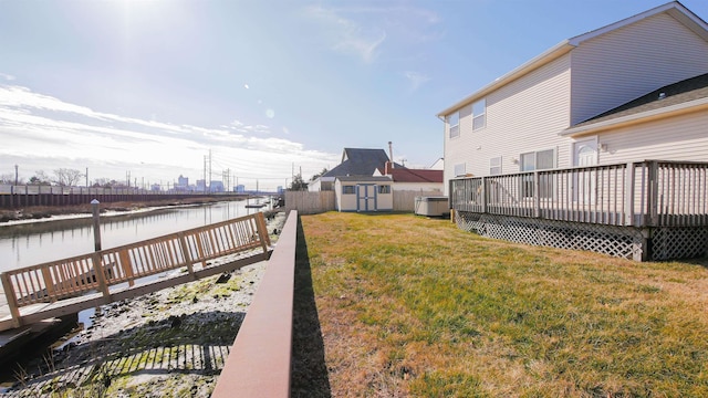 view of yard with a deck with water view and a shed