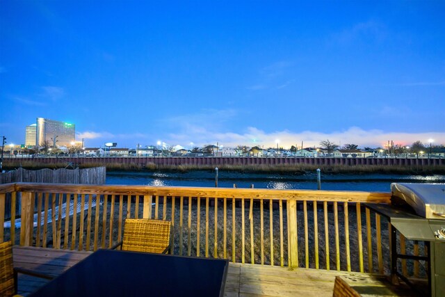 deck at dusk featuring a water view