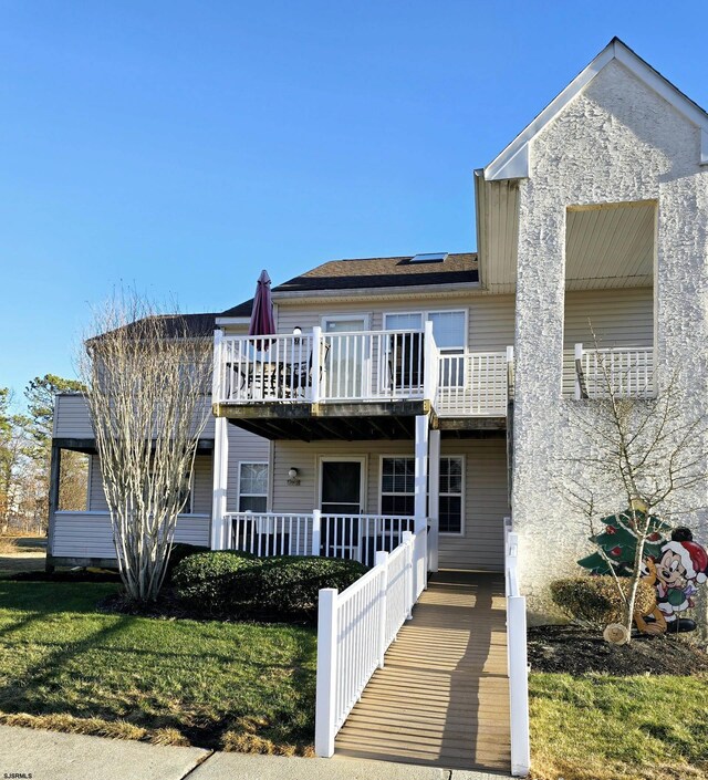 view of front of home with a balcony, a front lawn, and solar panels