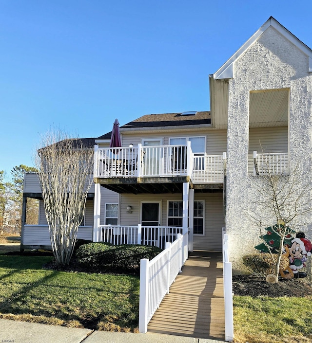 view of front of home with a balcony, a front lawn, and solar panels