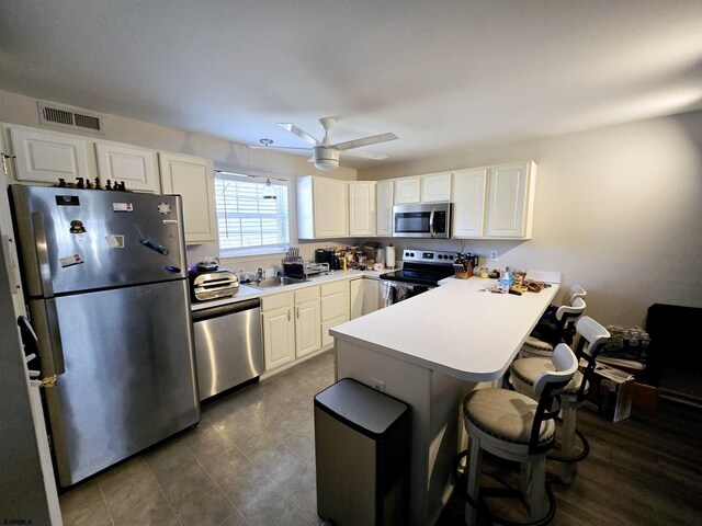 kitchen featuring appliances with stainless steel finishes, a breakfast bar area, white cabinets, and kitchen peninsula