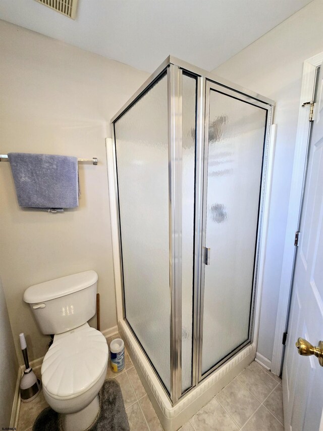 bathroom featuring walk in shower, toilet, and tile patterned flooring