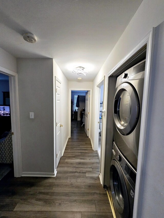 laundry room featuring stacked washing maching and dryer and dark hardwood / wood-style floors