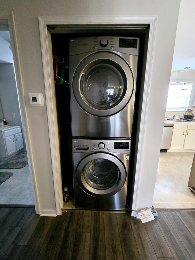 laundry area with stacked washer and dryer and dark hardwood / wood-style floors