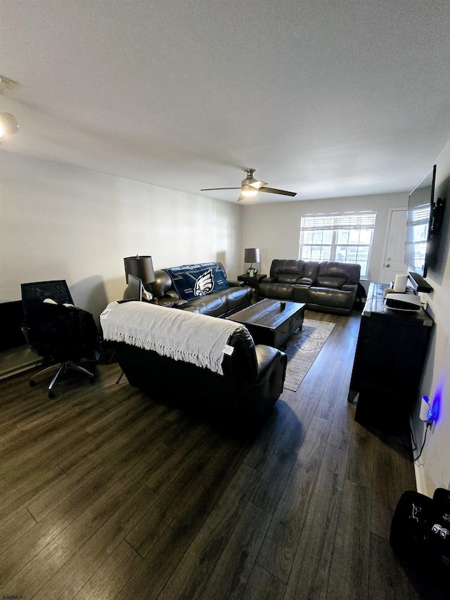 living room with dark wood-type flooring, ceiling fan, and a textured ceiling