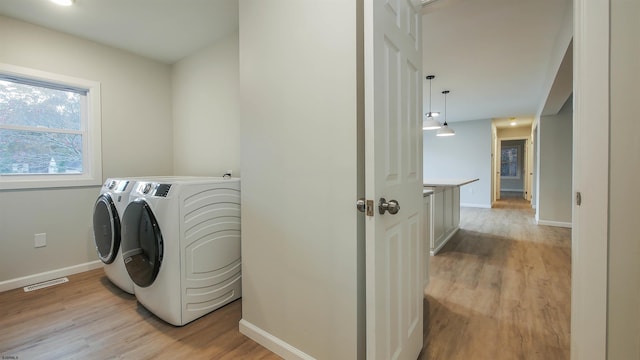 laundry area featuring light hardwood / wood-style flooring and washing machine and clothes dryer