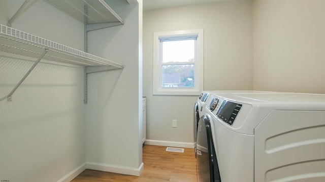 laundry room with light hardwood / wood-style floors and washing machine and dryer