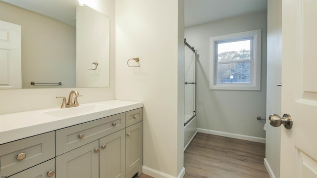 bathroom with vanity, hardwood / wood-style flooring, and bath / shower combo with glass door