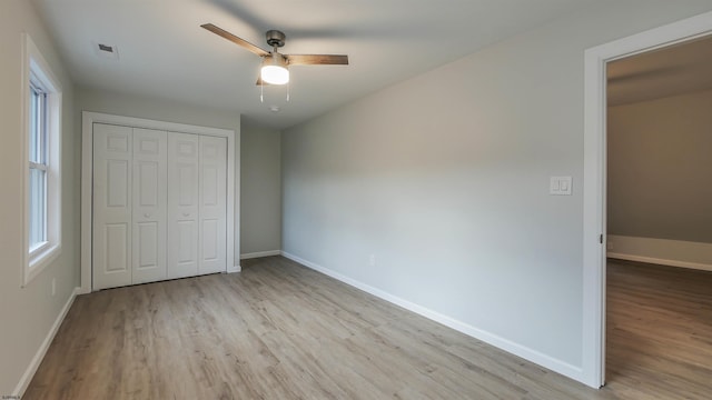 unfurnished bedroom with ceiling fan, a closet, and light wood-type flooring