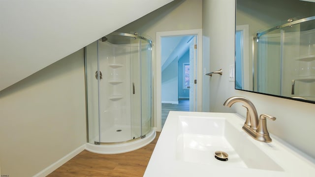 bathroom with lofted ceiling, hardwood / wood-style floors, vanity, and a shower with shower door