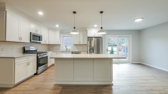 kitchen with white cabinetry, stainless steel appliances, a kitchen island, and pendant lighting