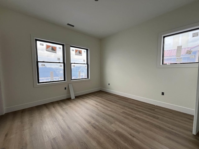 empty room with hardwood / wood-style flooring and a wealth of natural light