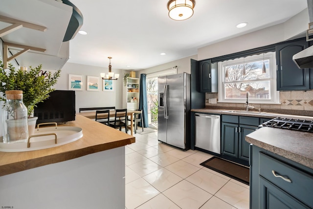 kitchen with blue cabinetry, stainless steel appliances, sink, a healthy amount of sunlight, and backsplash