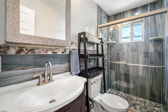 bathroom featuring vanity, toilet, a shower with shower door, and tile walls