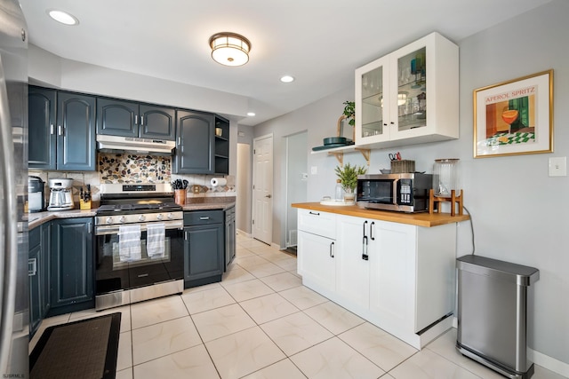 kitchen featuring light tile patterned floors, wooden counters, appliances with stainless steel finishes, white cabinetry, and tasteful backsplash