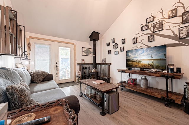 living room featuring light wood-type flooring, french doors, vaulted ceiling, and a wood stove