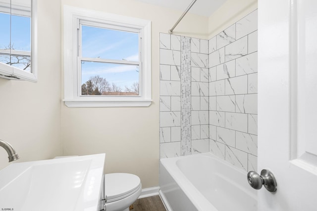 full bathroom featuring a healthy amount of sunlight, toilet, tiled shower / bath combo, and sink