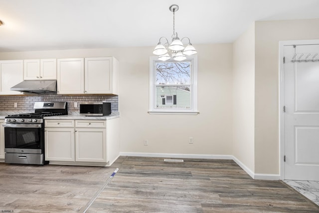 kitchen with white cabinetry, backsplash, stainless steel appliances, decorative light fixtures, and light wood-type flooring