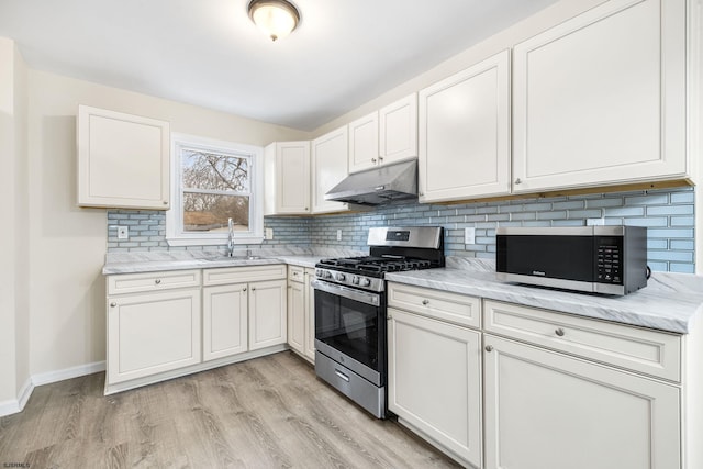 kitchen with sink, backsplash, stainless steel appliances, white cabinets, and light wood-type flooring