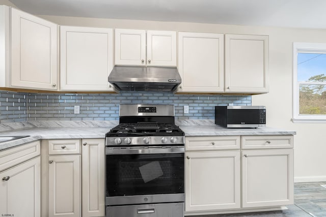 kitchen with stainless steel appliances, tasteful backsplash, light stone countertops, and white cabinetry