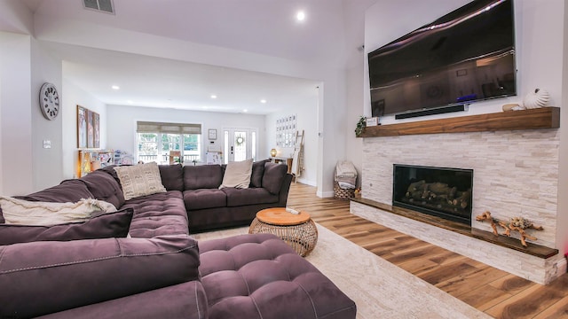 living room with a stone fireplace and hardwood / wood-style floors