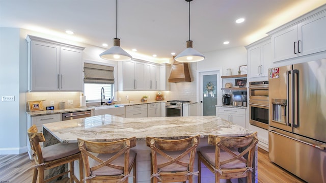 kitchen featuring pendant lighting, stainless steel appliances, a center island, and custom exhaust hood