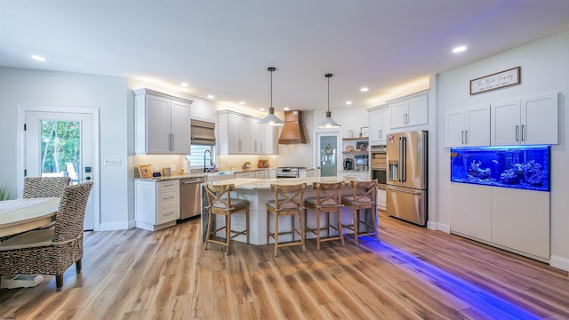 kitchen featuring appliances with stainless steel finishes, hanging light fixtures, a center island, white cabinets, and custom exhaust hood