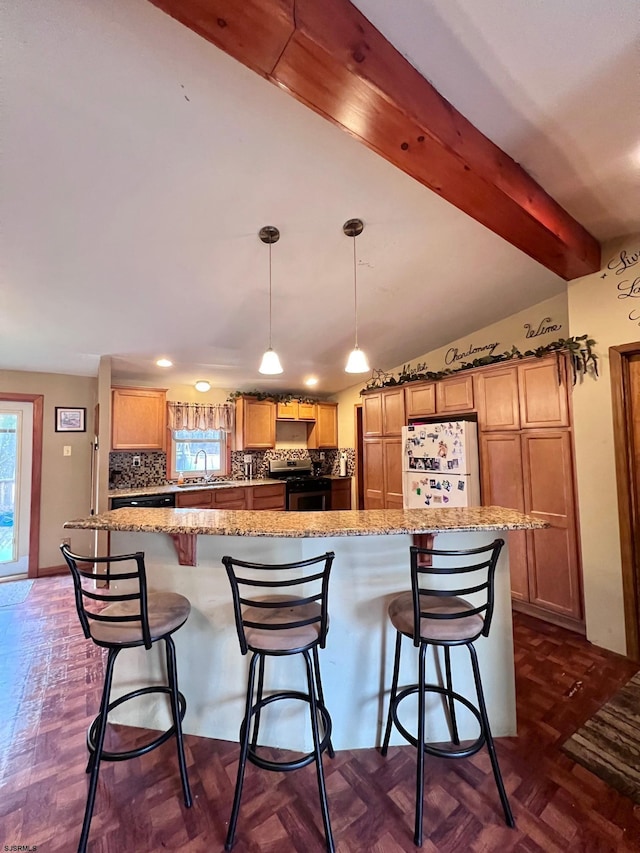 kitchen featuring a kitchen bar, white refrigerator, hanging light fixtures, dark parquet flooring, and stainless steel gas range oven