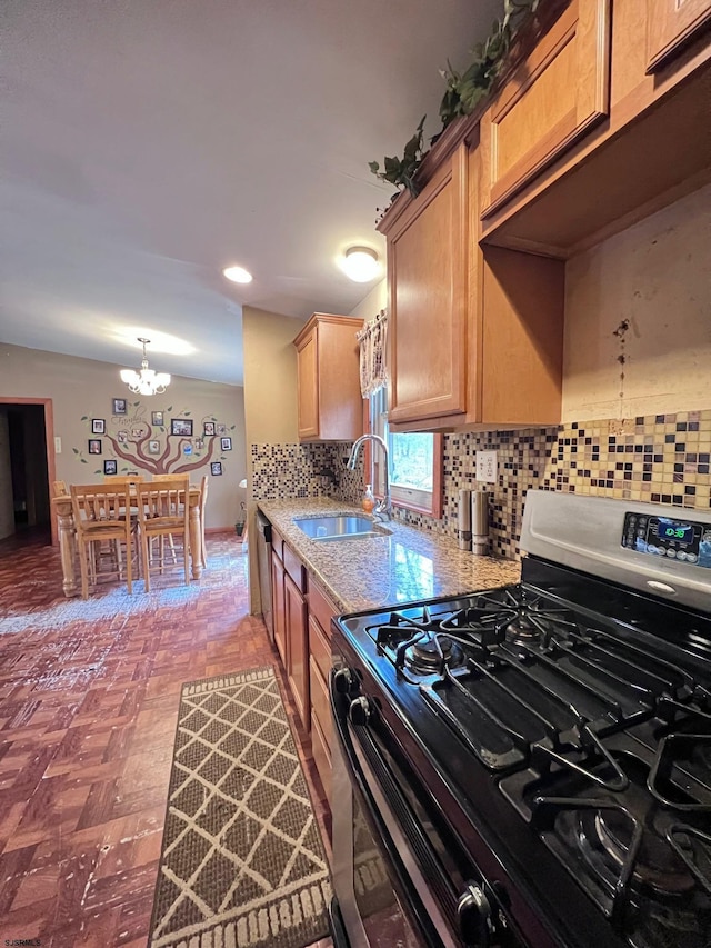 kitchen with sink, a chandelier, hanging light fixtures, appliances with stainless steel finishes, and backsplash